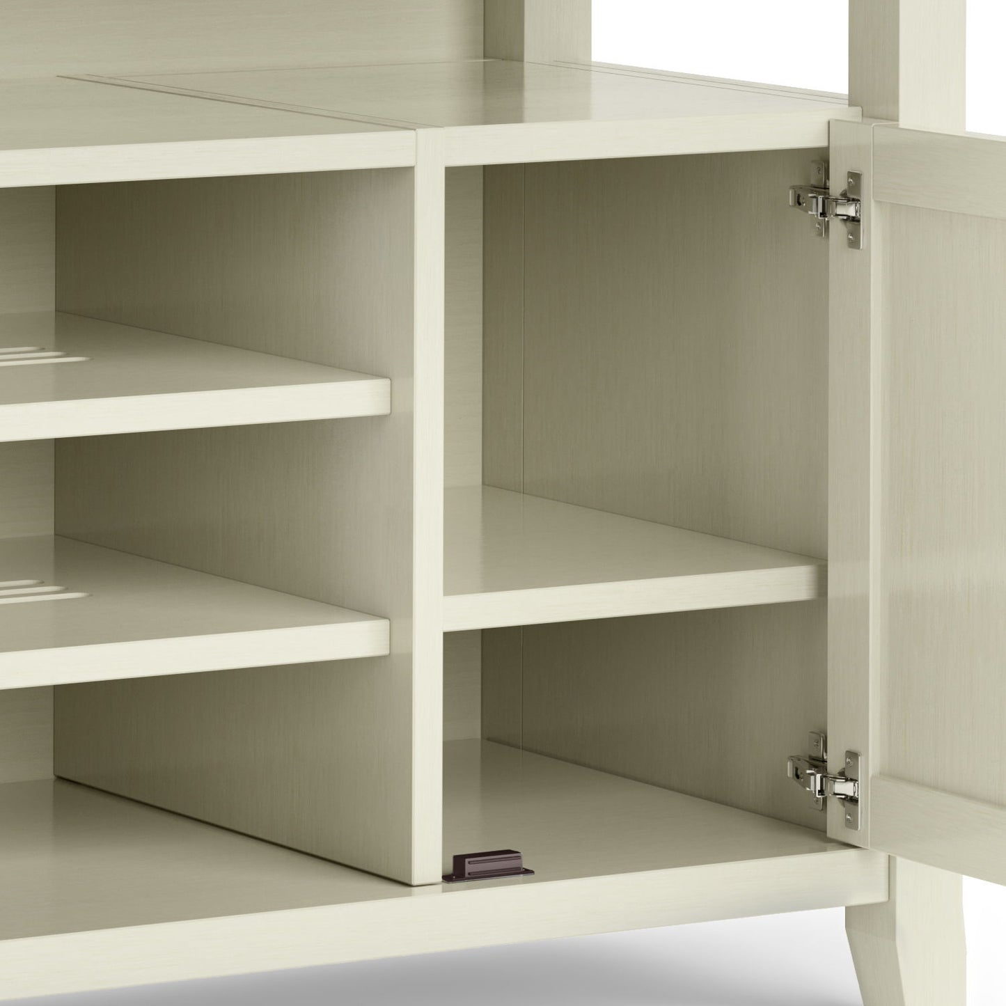 The Amherst - TV Media Stand, Handcrafted, features a cream-colored wood-finish cabinet with metal door hinges on the right, revealing two shelves inside—one placed lower—and a small black item in the bottom right corner.
