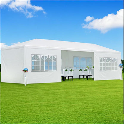 A 10x20' Outdoor Garden Gazebo Wedding Party Tent Canopy Marquee with removable sidewalls stands on green grass under a blue sky. Inside, tables and chairs are decorated with flowers. Arched windows let in sunlight.