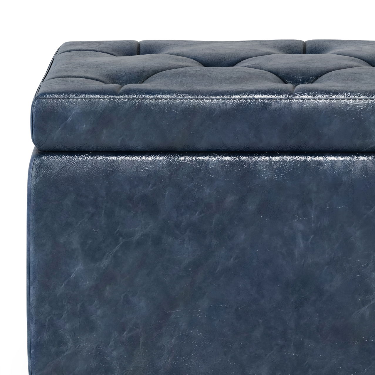 A close-up of the Hamilton Upholstered Storage Ottoman, featuring dark blue tufted leather with a stitched, padded top and smooth sides.
