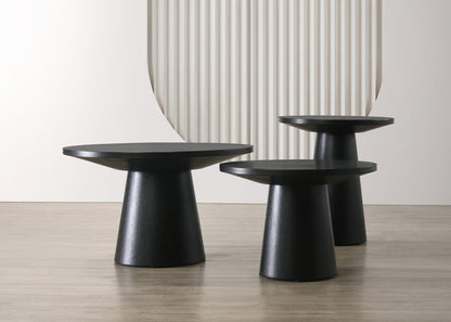 The Jasper 3 Piece Coffee, End, and Console Table set in Ebony Black is displayed on a light wood floor with a white wall and textured, curved backdrop.