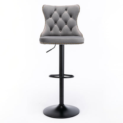 A set of 2 modern, gray Swivel Velvet Barstools with tufted backs, curved backrests, studded trim, black pedestal bases with footrests, and adjustable seat height—ideal for home pubs or kitchen islands. Set against a white background.