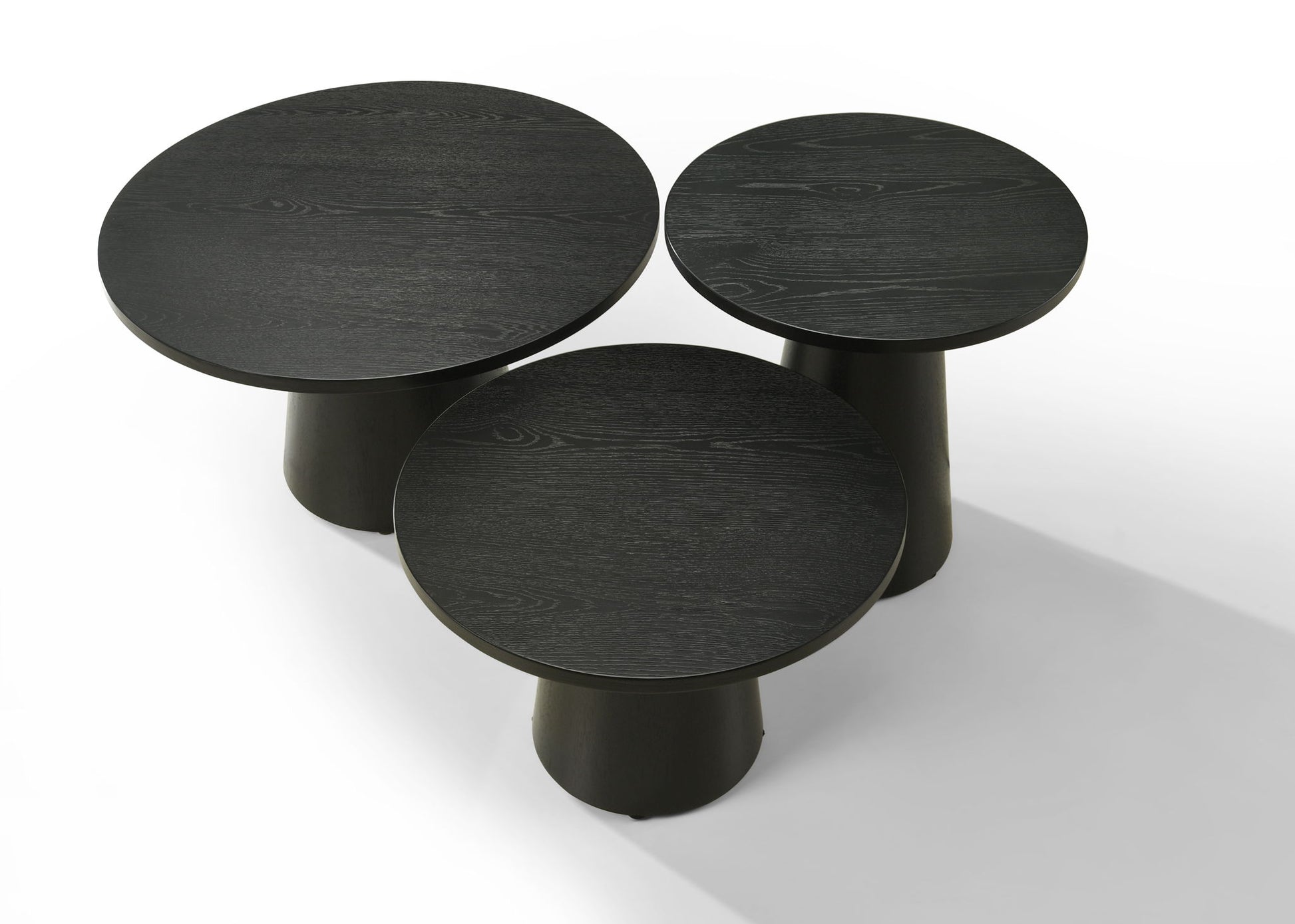 The Jasper 3 Piece Coffee, End, and Console Table Set in Ebony Black features three round wooden tables of different heights arranged together on a white background for a modern, minimalist look.