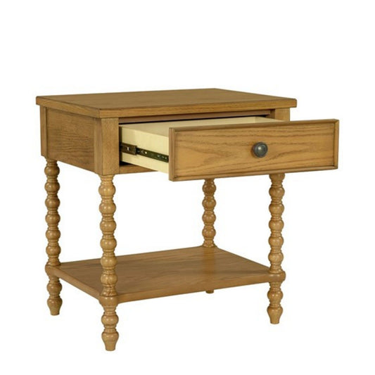 The Traditional Durable Nightstand Table With Drawer And Shelf features contoured spindle legs, an open lower shelf, and a single drawer with a round metal knob. The wood has a light, warm finish.