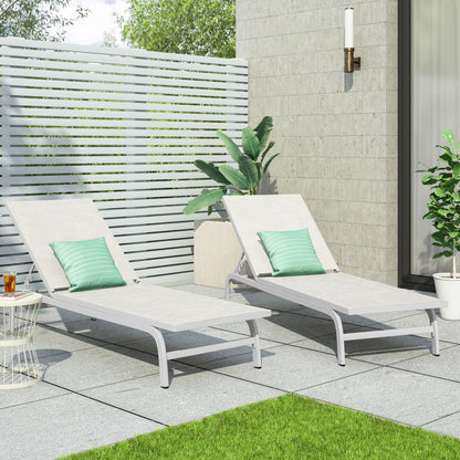 Two Finn Contemporary Chaise Lounges with green-striped pillows sit on a gray-tiled patio. Nearby are potted plants, a drink on a white table, a slatted privacy fence, and a modern wall sconce.