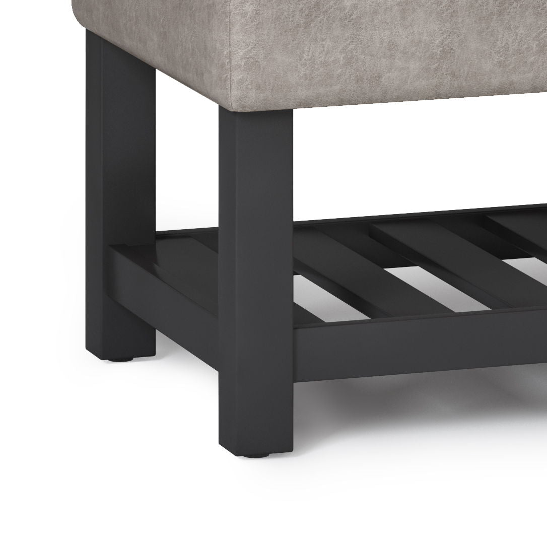 Close-up of the Cosmopolitan Storage Ottoman Bench with a cushioned light gray upholstered seat, sturdy black wooden legs, and an open bottom slatted shelf.