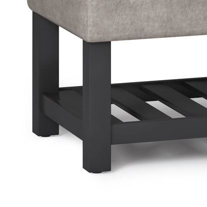 Close-up of the Cosmopolitan Storage Ottoman Bench with a cushioned light gray upholstered seat, sturdy black wooden legs, and an open bottom slatted shelf.