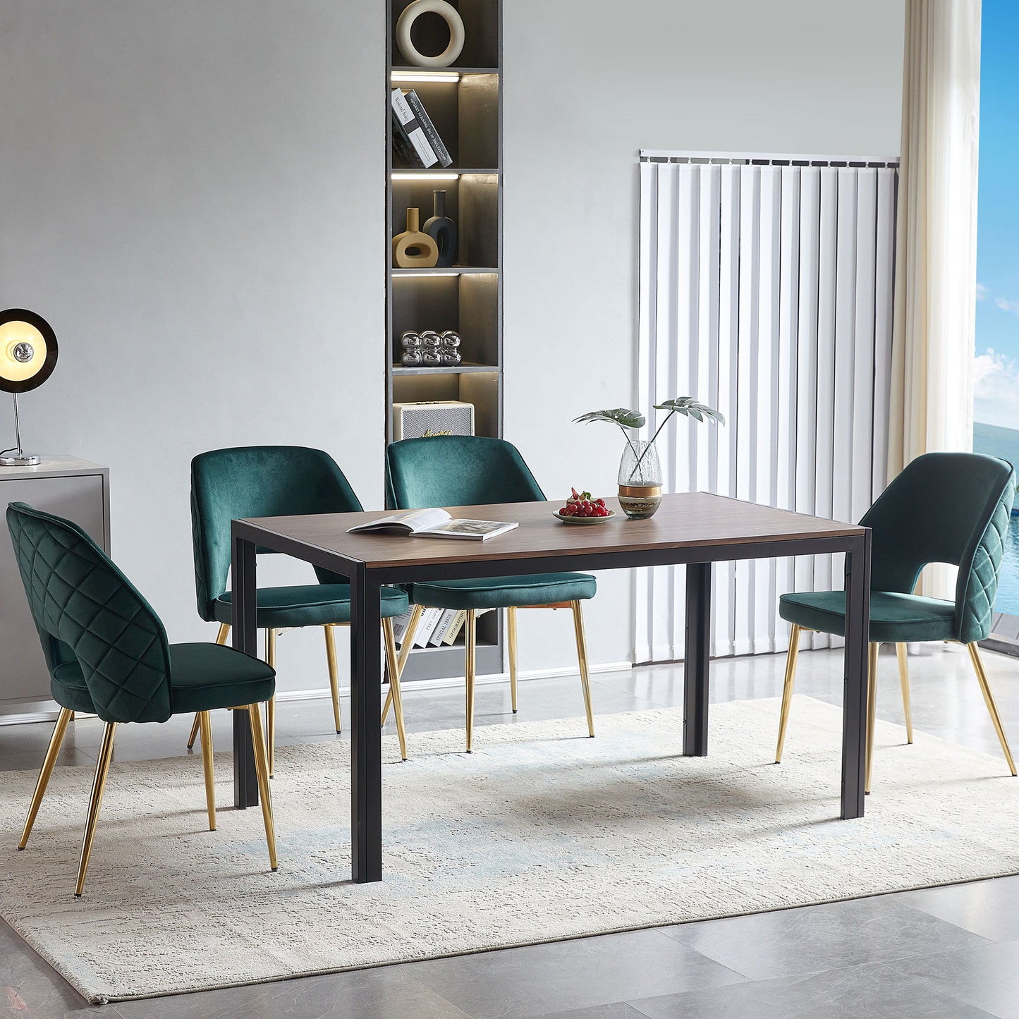 A modern dining area features a rectangular wooden table, four Velvet Dining Chairs With Metal Legs And Hollow Back Upholstered Dining Chairs in green, a white rug, a minimalist shelf with decor items, light gray walls, and vertical blinds over the window.