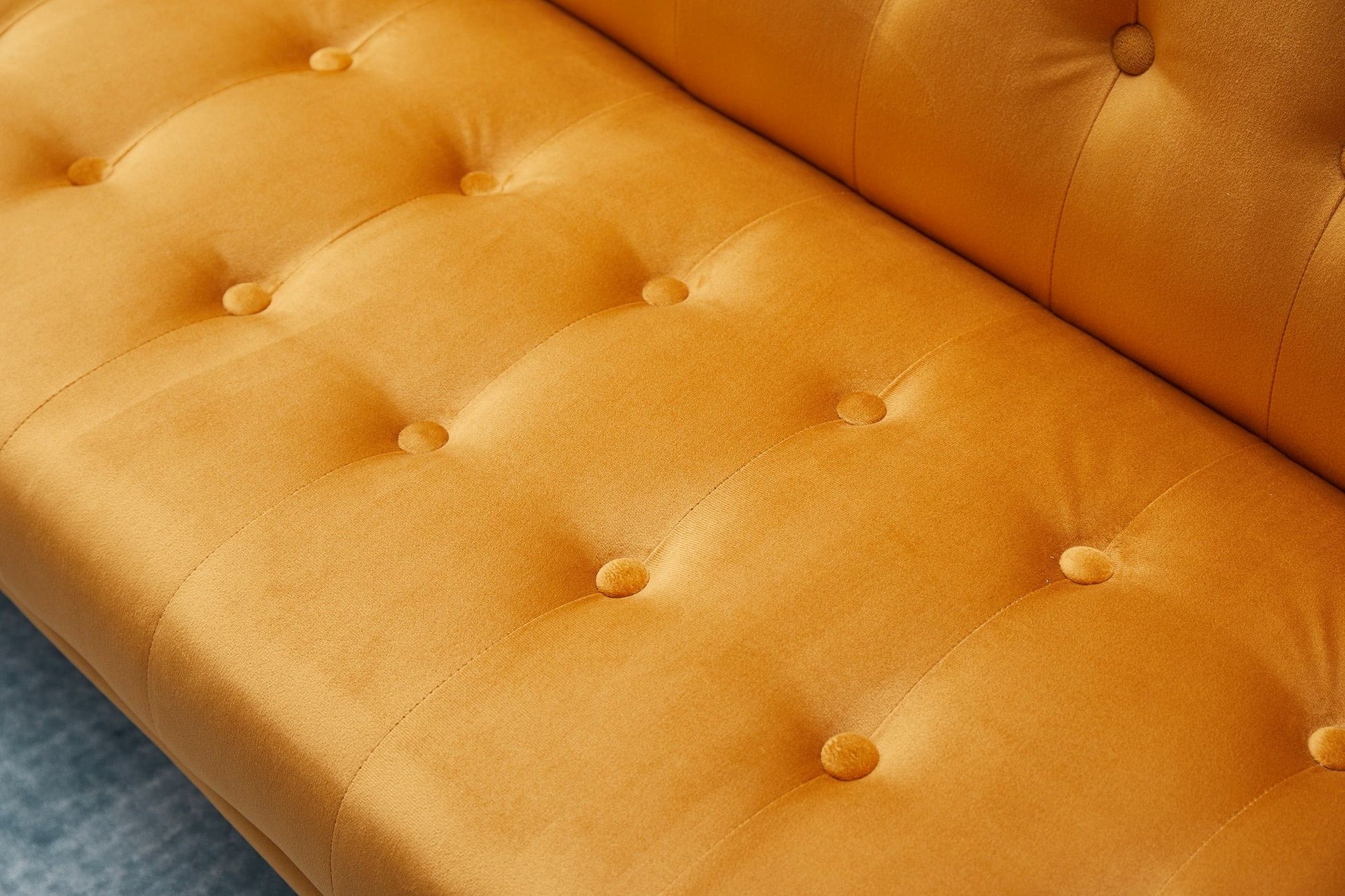 Close-up of the Comfort Compact Design Sofa Bed in yellow, featuring a soft velvety texture and button tufting on the seat and backrest, set against a gray floor.