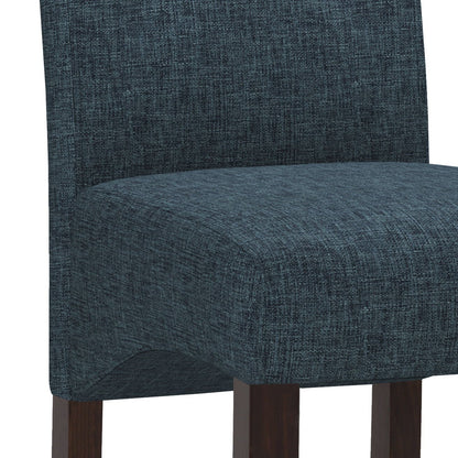 A close-up of the Cosmopolitan - Deluxe Tufted Parson Upholstered Chair (Set of 2) featuring dark blue textured fabric and dark wooden legs.