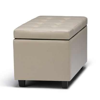 The Cosmopolitan Upholstered Storage Ottoman is rectangular, beige, and tufted with a cushioned lid and short black legs, displayed on a white background.