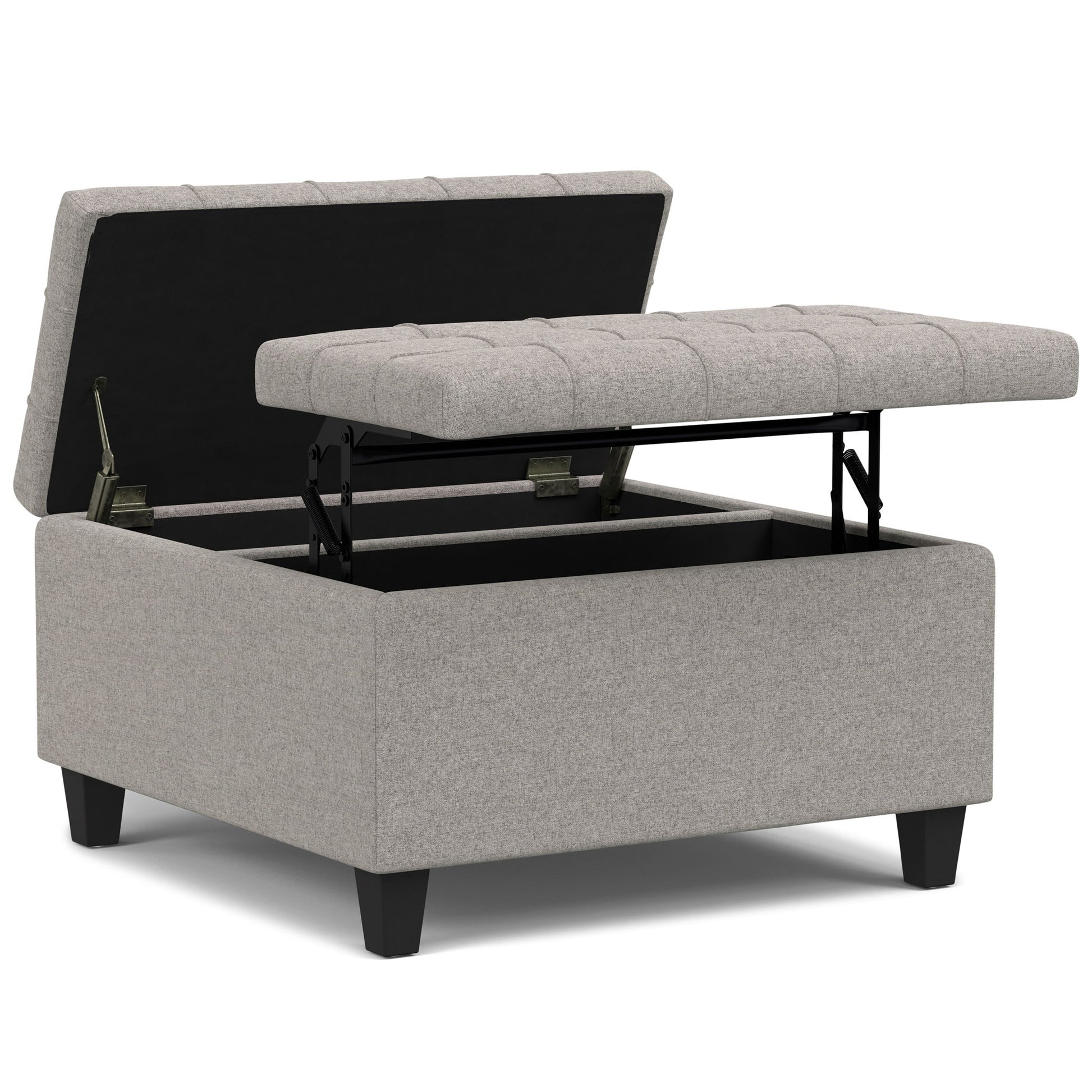The Harrison Upholstered Coffee Table Storage Ottoman features a light gray tufted top that opens on metal hinges to reveal spacious storage inside, and stands on four short black legs.