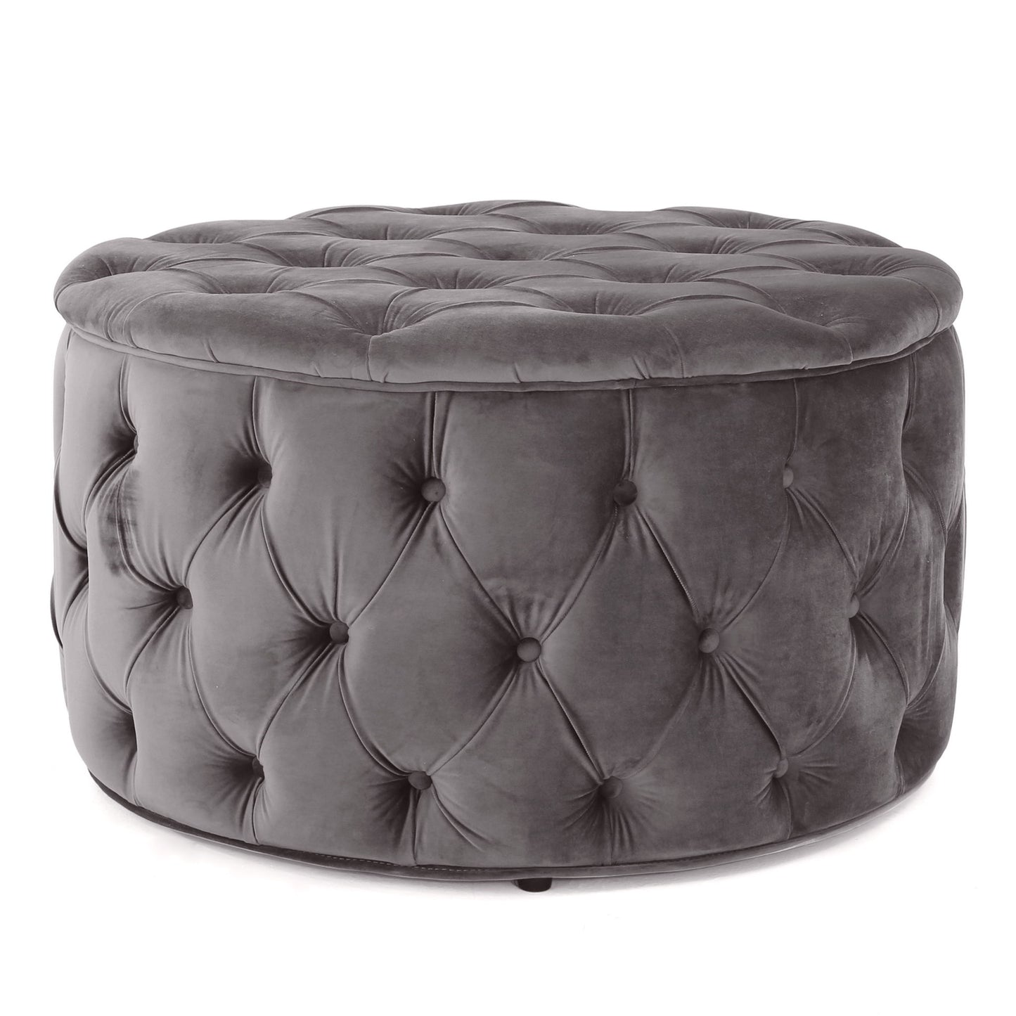 The Modern Glam Ottoman Velvet is a round ottoman, upholstered in dark gray velvet with a plush cushioned top and button-tufted sides.