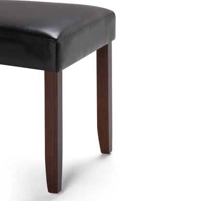 A close-up of the Acadian - Upholstered Parson Dining Chair (Set of 2), featuring a black leather seat and dark wooden legs, shown on a white background.