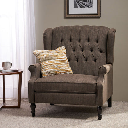 The Dunham Contemporary Fabric Tufted Oversized Pushback Recliner, featuring a brown upholstered finish and wooden legs, sits beside a round side table. A striped pillow accents the chair, with a framed black-and-white photo on the beige wall behind.