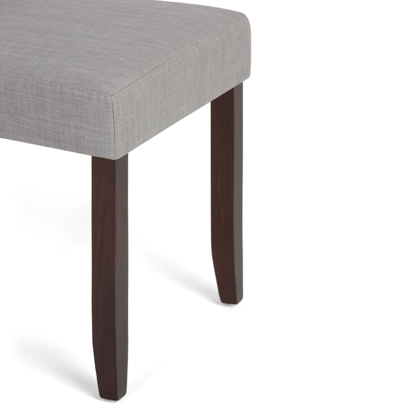 A close-up of the Acadian - Upholstered Parson Dining Chair (Set of 2) shows its light gray upholstered seat and dark wooden legs against a white background.