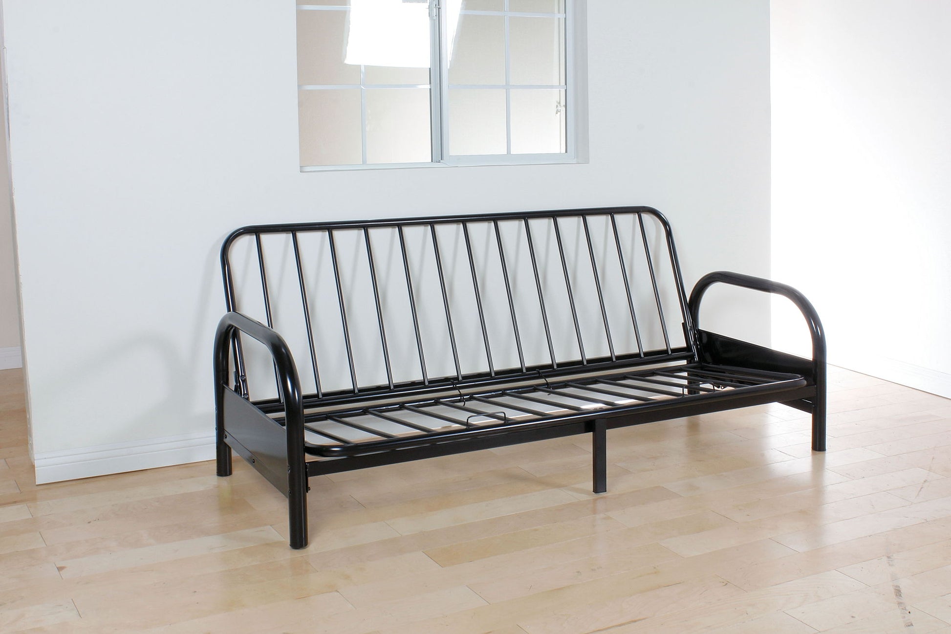 The Alfonso Adjustable Sofa Frame (Cushion Not Included) in black metal with simple slats is shown on a light wood floor in a bright room with white walls and a window, without any mattress or cushions.
