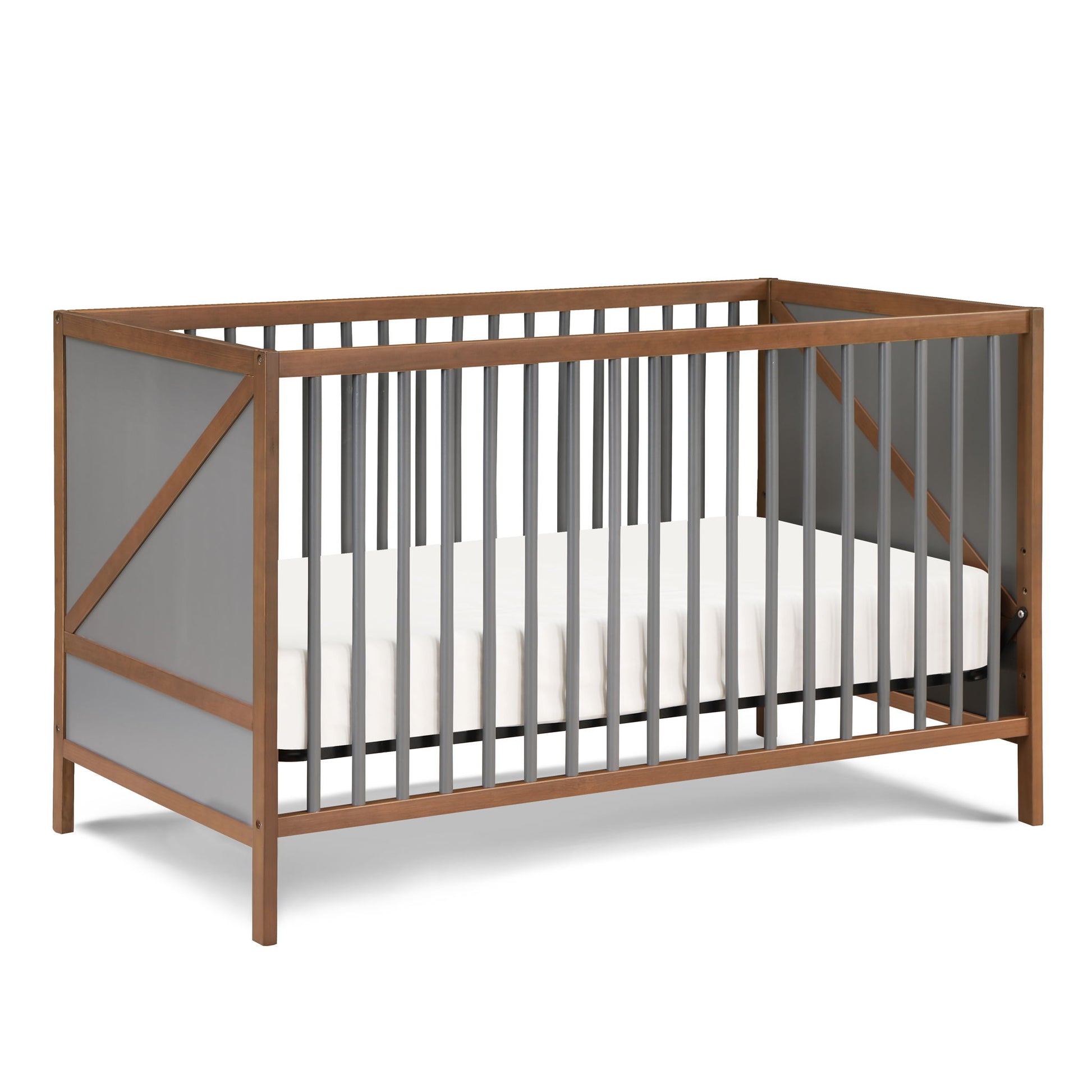 The Pixie Zen 3-in-1 Crib in Walnut features a modern wooden frame, gray slats, and angled side design. It includes a white mattress with no bedding or decorations.