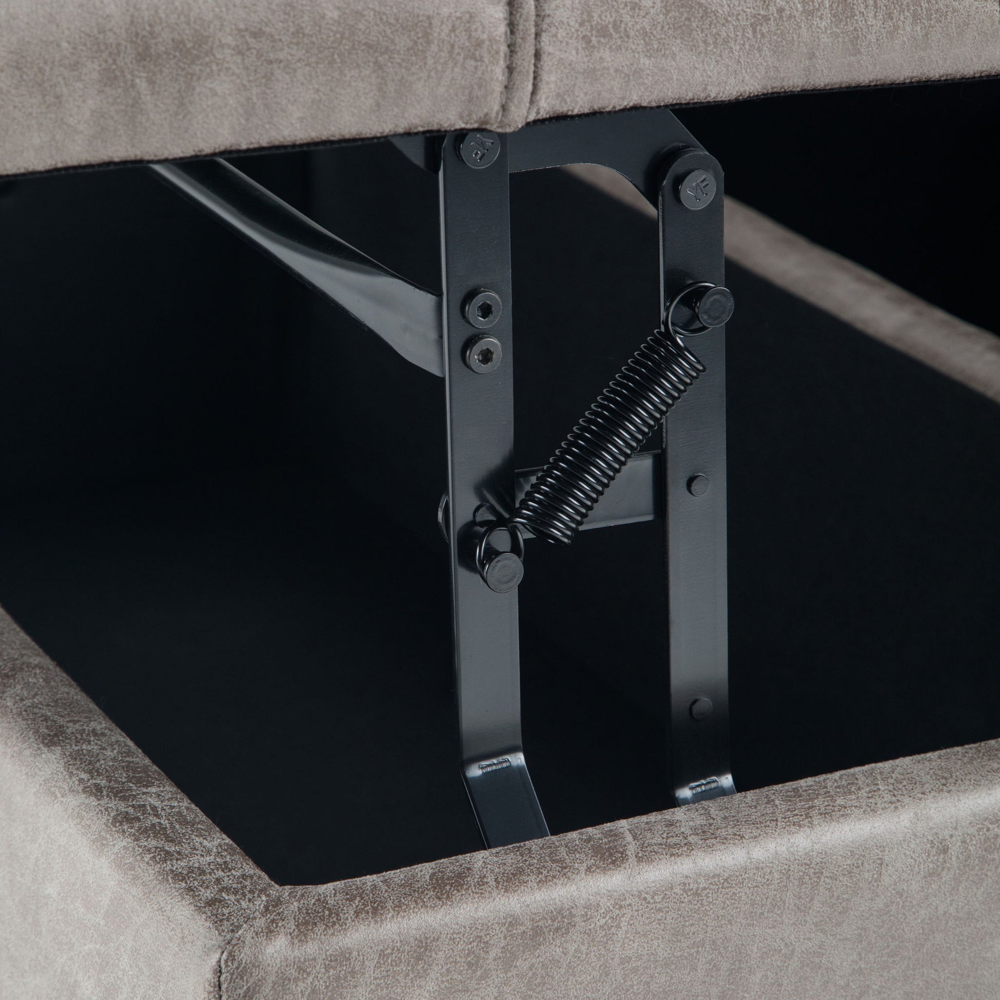 Close-up of the metal hinge and spring mechanism inside the Harrison - Upholstered Coffee Table Storage Ottoman, highlighting the opening hardware beneath its lifted cushioned lid.