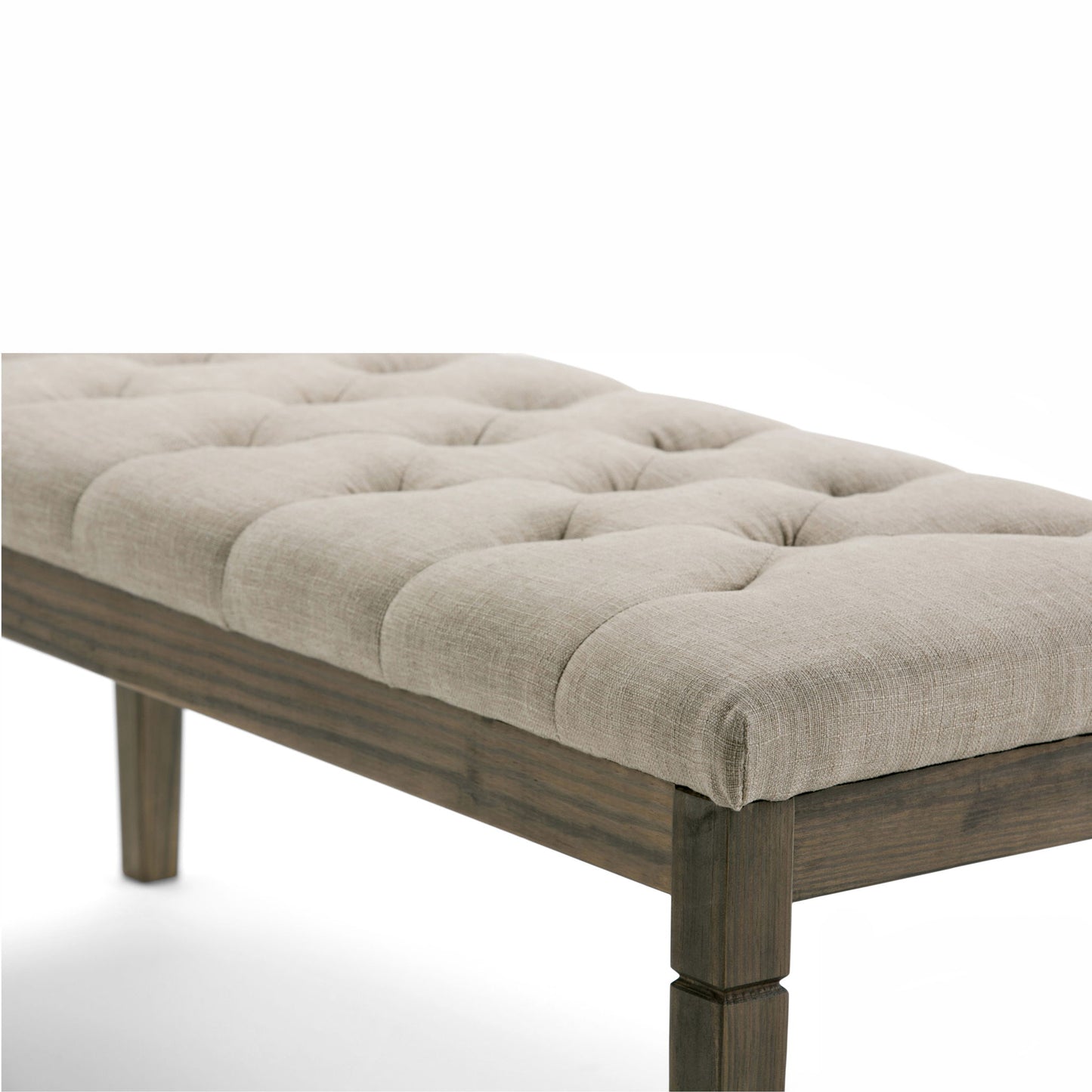 A close-up of the Waverly Upholstered Tufted Ottoman Bench, featuring a cushioned beige seat and sturdy wooden legs, highlights its elegant tufted texture and solid frame against a white background.