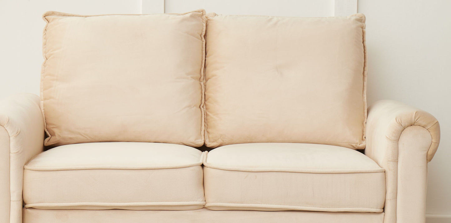 The Graceful Design Plush Comfort Loveseat, a beige two-seater with plush cushions and rolled arms, is set against a plain white wall.