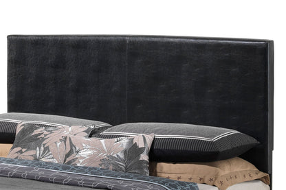 The Elegant Platform Bed For Relaxed Spaces features a black upholstered headboard behind pillows and bedding, styled with a mix of solid and leaf-patterned pillowcases in neutral tones.