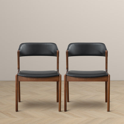 Two Enzo Dining Chairs (Set of 2) in black and brown stand side by side on a light herringbone-patterned floor, set against a plain beige wall.