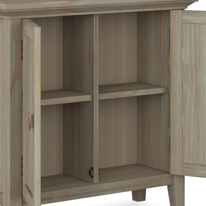 The Redmond - Handcrafted Low Storage Cabinet features two open doors revealing four storage spaces, formed by shelves dividing two vertical compartments. It is crafted from wood with a light, weathered finish.
