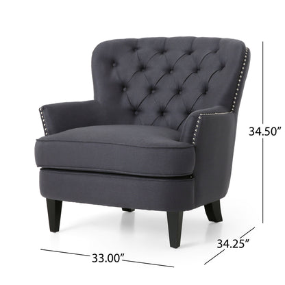 The Enchante Living Room Set features a dark gray tufted back club chair with silver nailhead trim, black wooden legs, padded arms, and a cushioned seat. Chair dimensions: 34.50" H x 33.00" W x 34.25" D. Includes ottoman.
