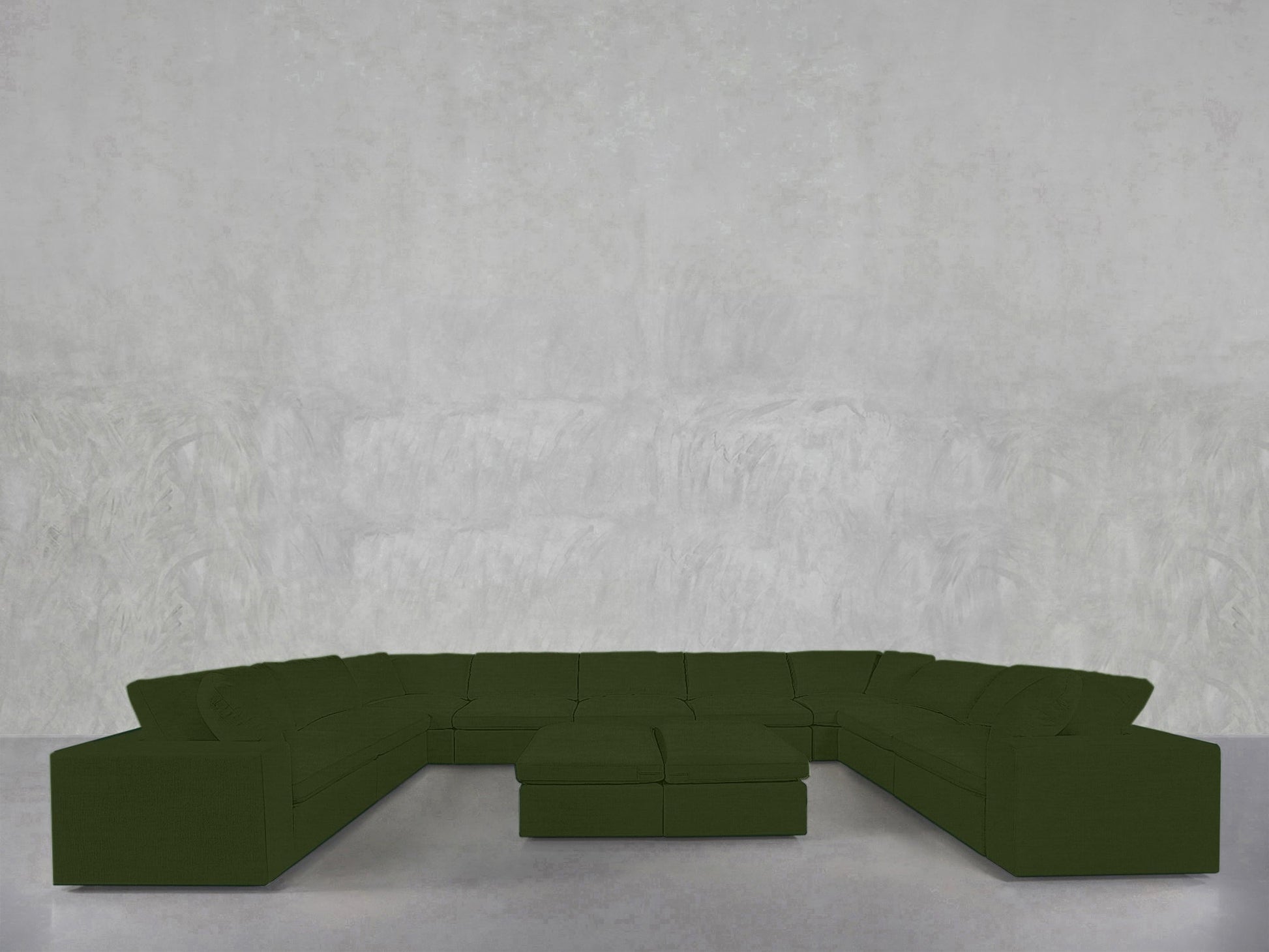 A 9-Seat Modular U-Sectional with Double Ottoman, in dark green, sits on a light gray floor against a textured pale gray wall.