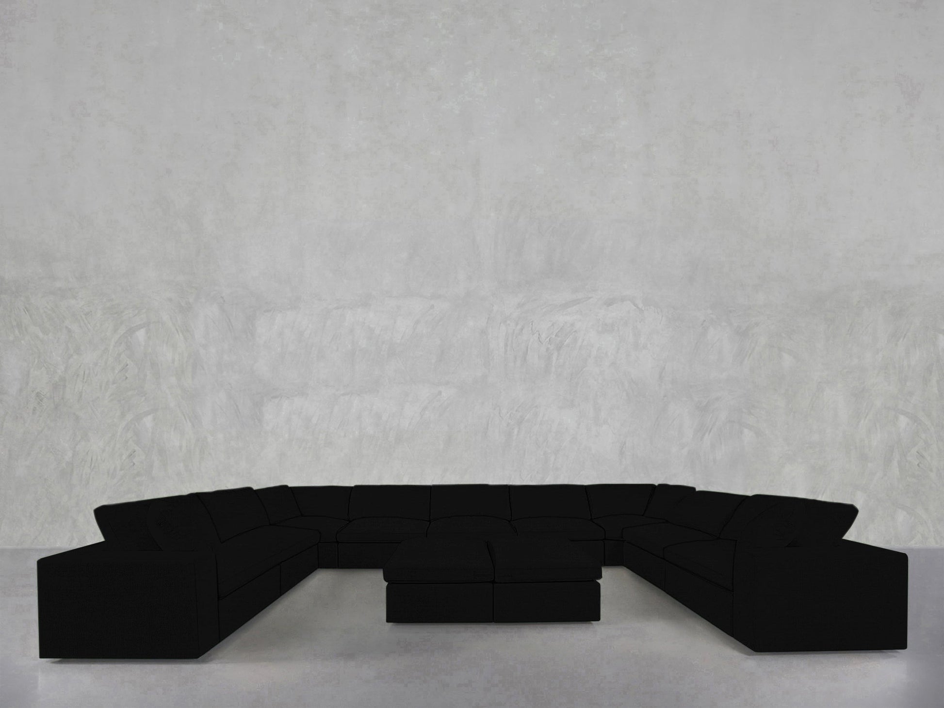 A 9-Seat Modular U-Sectional with Double Ottoman is arranged in a spacious, minimal room featuring light gray textured walls and a sleek light floor.