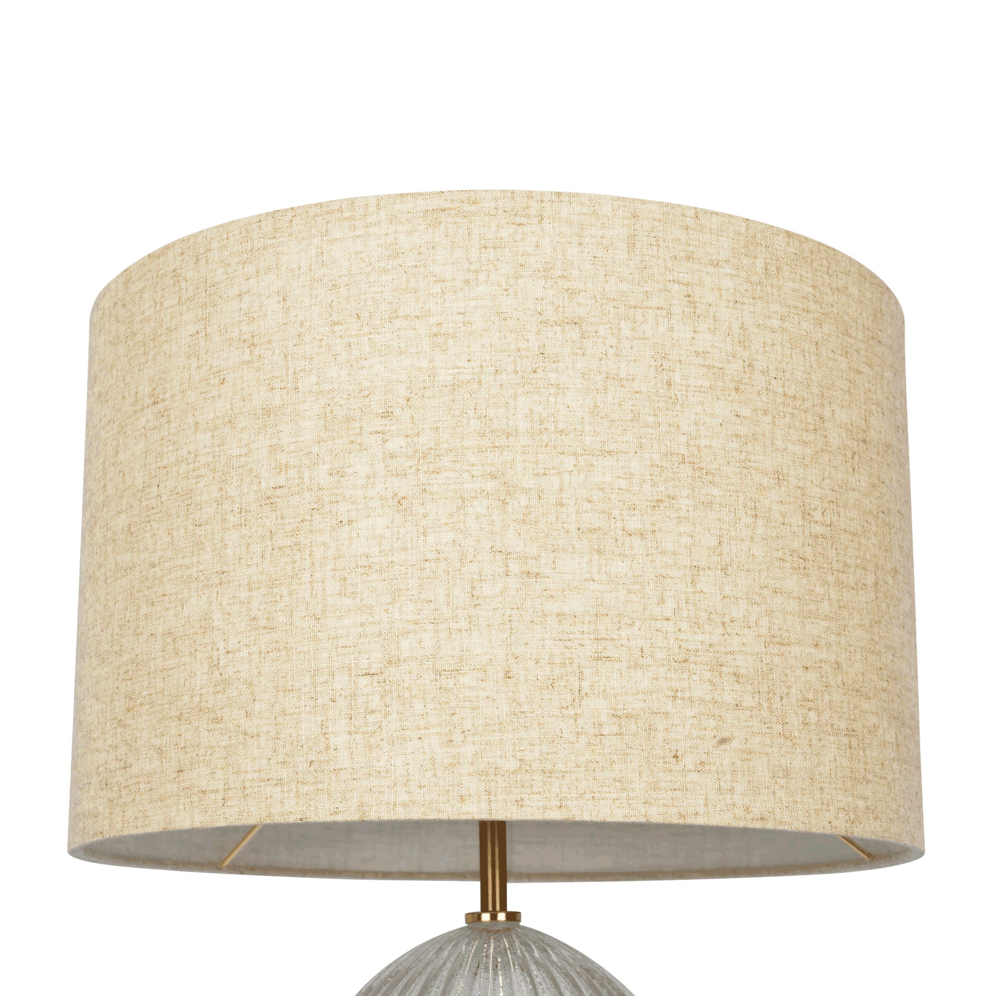 A close-up of the Aurora table lamp features a large, beige linen cylindrical shade with textured fabric, resting on a ribbed clear base. The metal rod beneath is gold-toned, set against a plain white background.