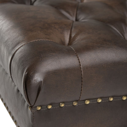 Close-up of the Henley Tufted Ottoman Bench in distressed brown leather, featuring button tufting and brass nailhead trim along the edge. The leather upholstery is smooth with a subtle sheen.