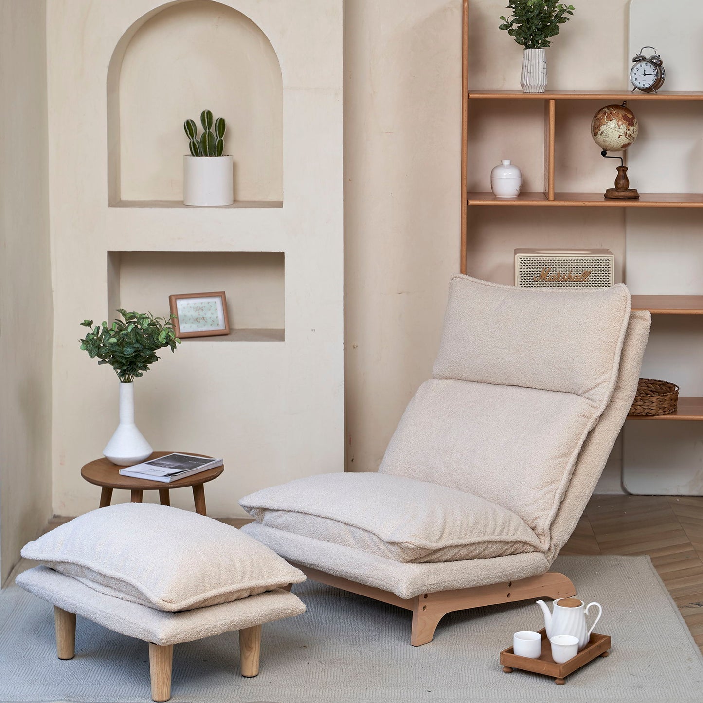 A Single Lazy Sofa Chair Leisure Foldable Reclining Chair in beige with a footrest sits by a small wooden table holding a potted plant and magazines. Nearby, shelves display decor like a globe and framed photo in a softly lit, minimalist room.