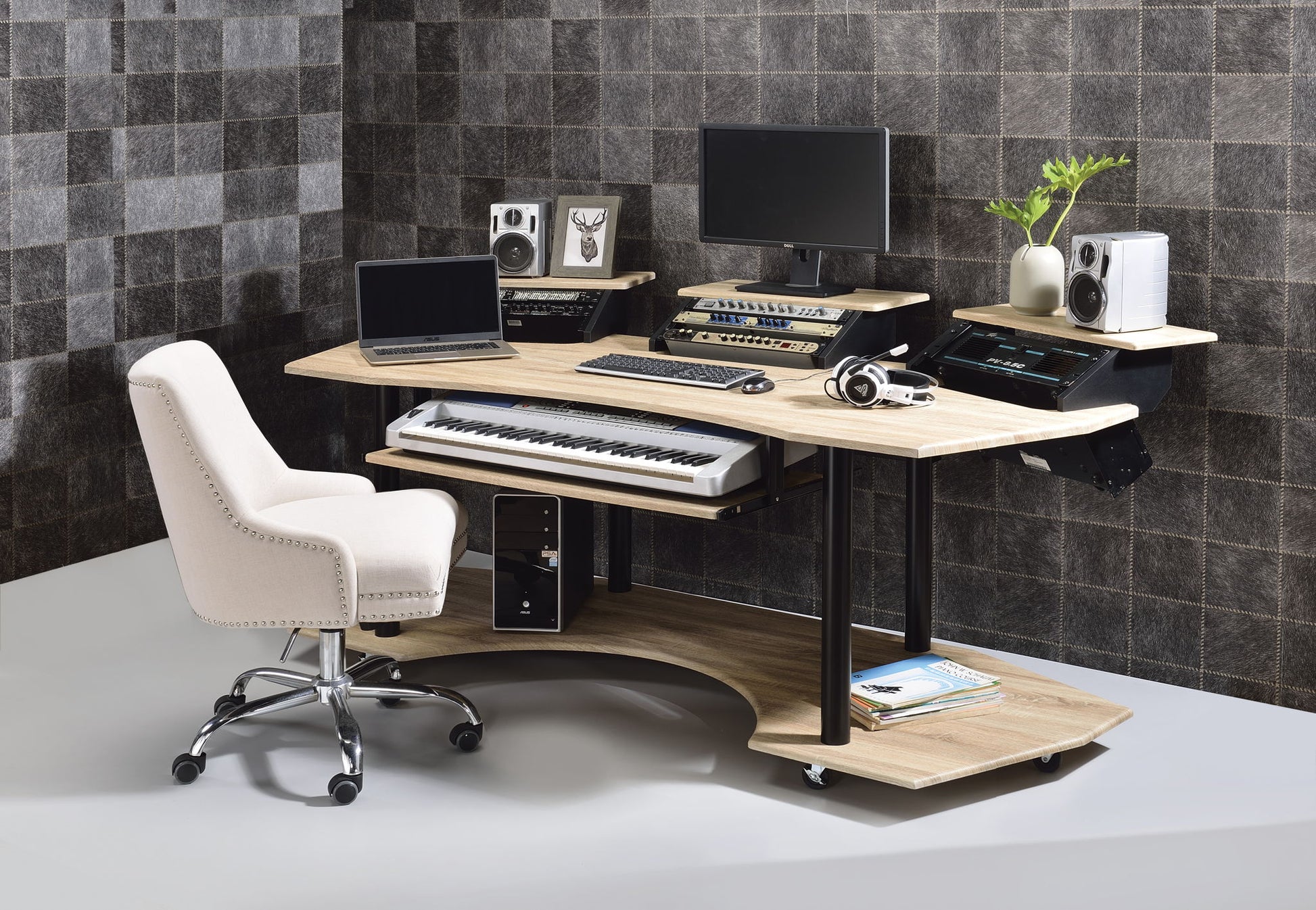The Eleazar Music Recording Studio Desk - Wood features a computer monitor, laptop, MIDI keyboard, audio interfaces, speakers, headphones, and a white cushioned office chair against a gray checkered wall.
