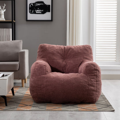 A Soft Teddy Fabric Tufted Foam Bean Bag Chair in dusty rose is placed on a patterned rug in a modern living room featuring a gray sofa, white coffee table, framed wall art, and a tall window with white blinds.