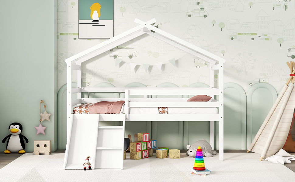A children's bedroom with a white Low Loft House Bed with Slide, Ladder, Safety Guardrails, and House Roof Frame. Pastel bedding adorns the bed; a teepee, toys, blocks, and penguin plush are on the floor. Light wallpaper shows building and vehicle outlines.