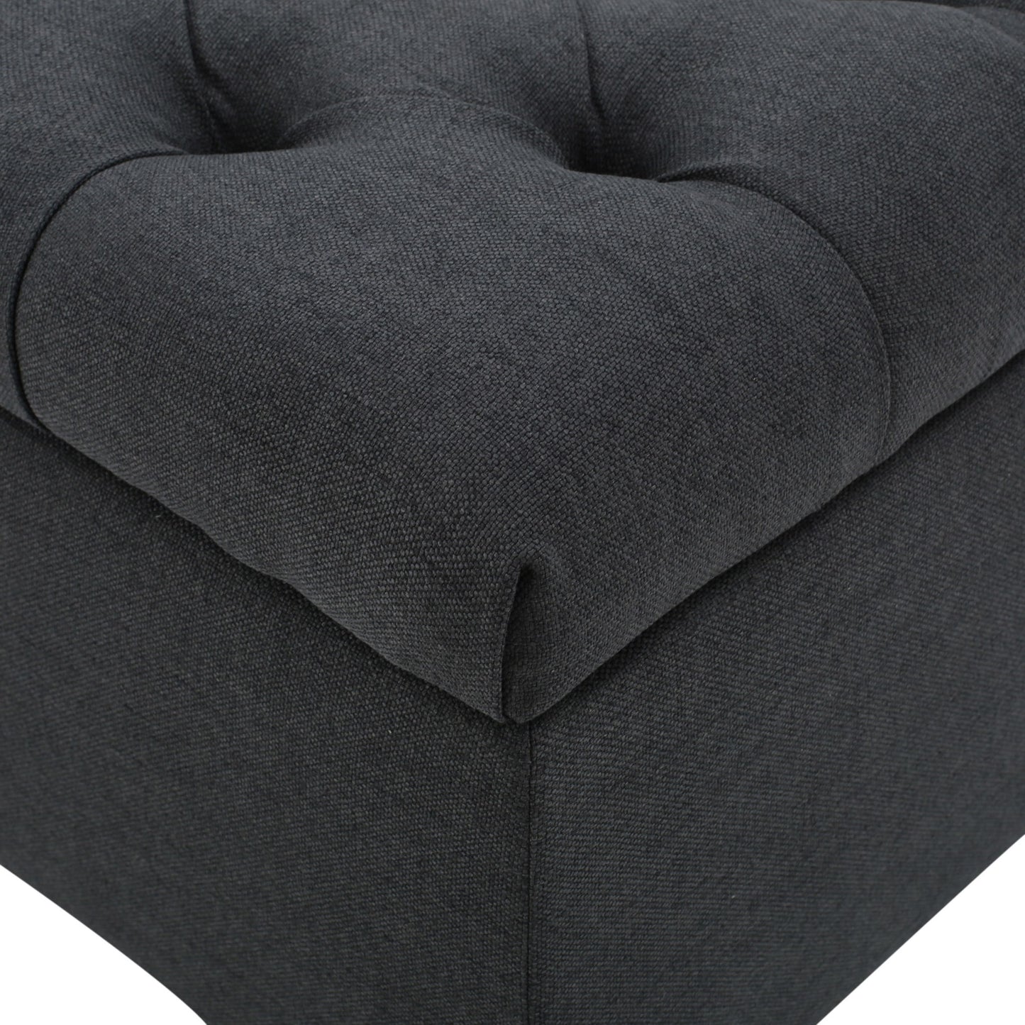 Close-up of the Glouster Contemporary Storage Ottoman, featuring dark grey fabric upholstery, visible stitching, and deep button tufted details.