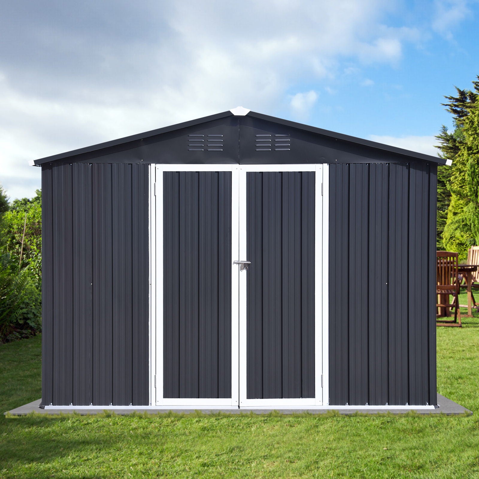 A 10'x12' Garden Sheds Outdoor Storage Shed in dark gray with white-trimmed double doors sits on a grassy lawn, surrounded by trees and outdoor furniture under a partly cloudy sky.