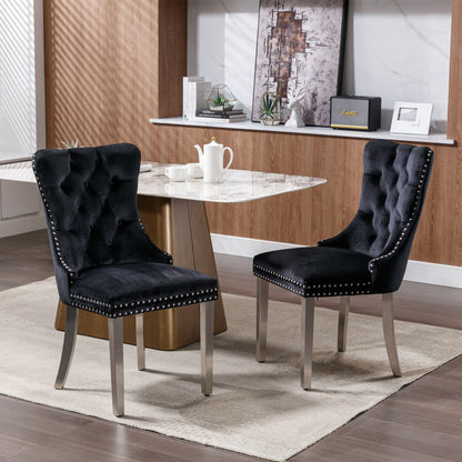 Two Nikki modern tufted velvet dining chairs with chrome-plated legs and nailhead trim (set of 2) sit on a light rug beside a marble-top table in a contemporary dining room with wood paneling and shelves.