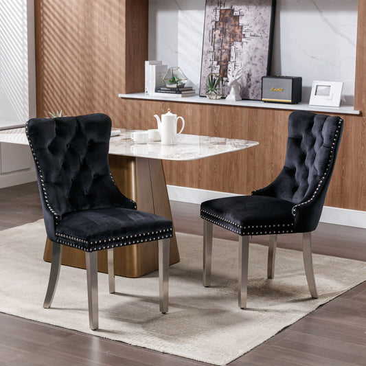 Two Nikki modern tufted velvet dining chairs with chrome-plated legs and nailhead trim (set of 2) sit on a light rug beside a marble-top table in a contemporary dining room with wood paneling and shelves.