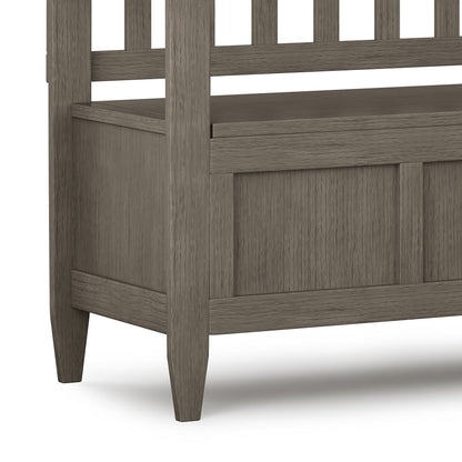 Close-up of the Brooklyn Handcrafted Entryway Storage Bench, featuring a slatted backrest, panel detailing, four legs, a grayish-brown finish, and a lift-top seat for storage.