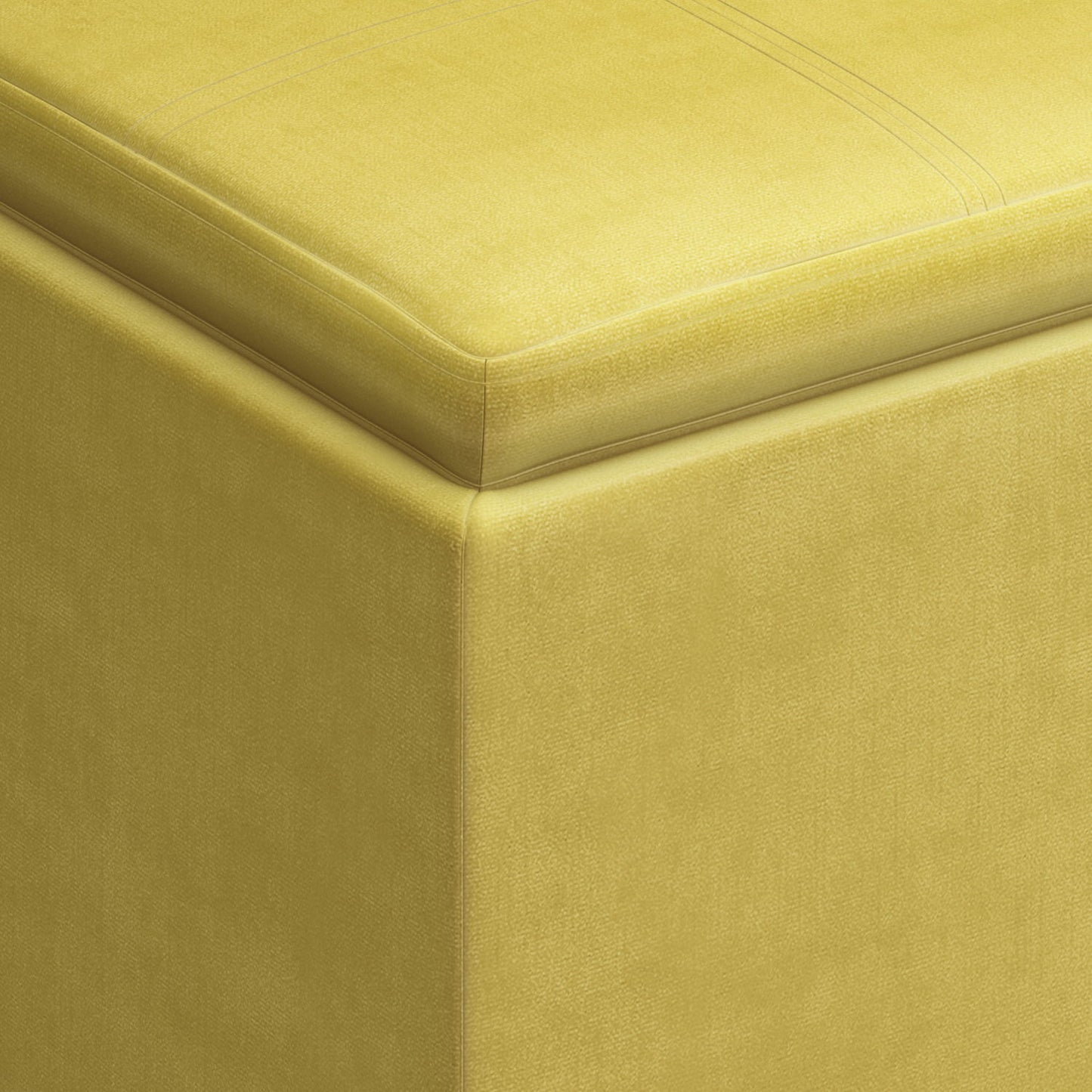 Close-up of the corner of the Rockwood - Upholstered Cube Storage Ottoman With Tray, highlighting its smooth yellow fabric texture and neat top stitching.