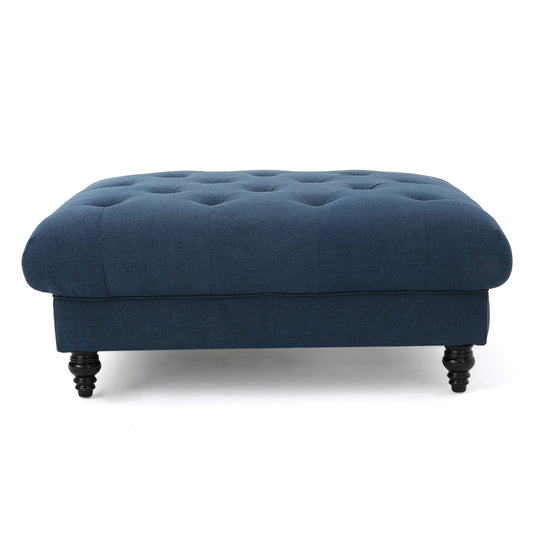 The Madrid - Tufted Ottoman Footrest is a large, rectangular piece upholstered in dark blue fabric with black turned wooden legs, displayed against a white background.