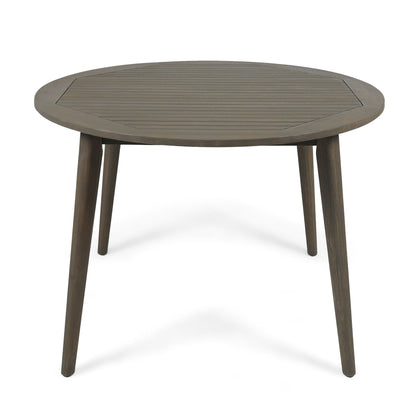 The Stamford Outdoor Dining Table features a round wooden slatted top and four angled legs, shown against a white background for a modern look.