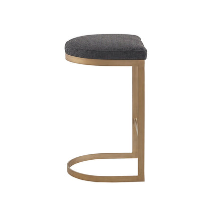 The Counter Stool With Upholstered Seat features a charcoal cushion and an antique gold metal base with a curved, semi-circular profile. Shown in side view against a white background.