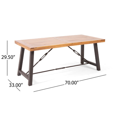 The Outdoor Dining Table With Slat Wooden Panel And Turnbuckle Accents - Teak features a slatted rectangular wooden top, black metal legs, and crossbars. Dimensions: 70"L x 33"W x 29.5"H.