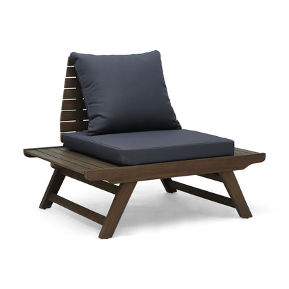 The Sedona Outdoor Club Chair features a slatted design, angled wooden legs, wide armrests, and dark seat and back cushions, shown against a white background.
