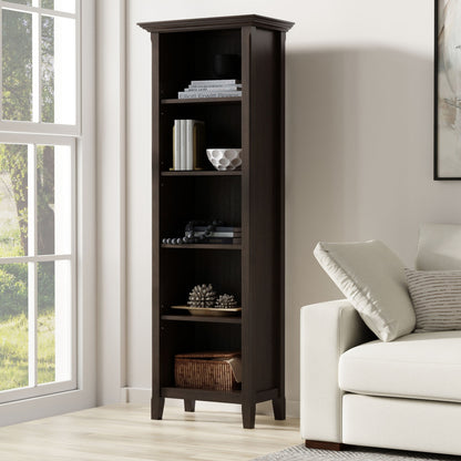 The Amherst 5 Shelf Bookcase in brown stands beside a white sofa in a bright living room with a large window, displaying books, decor, and a basket on its five spacious shelves.