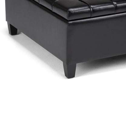 Close-up of the bottom corner of the Harrison - Large Coffee Table Storage Ottoman in black leather with short square wooden legs, placed on a white surface.