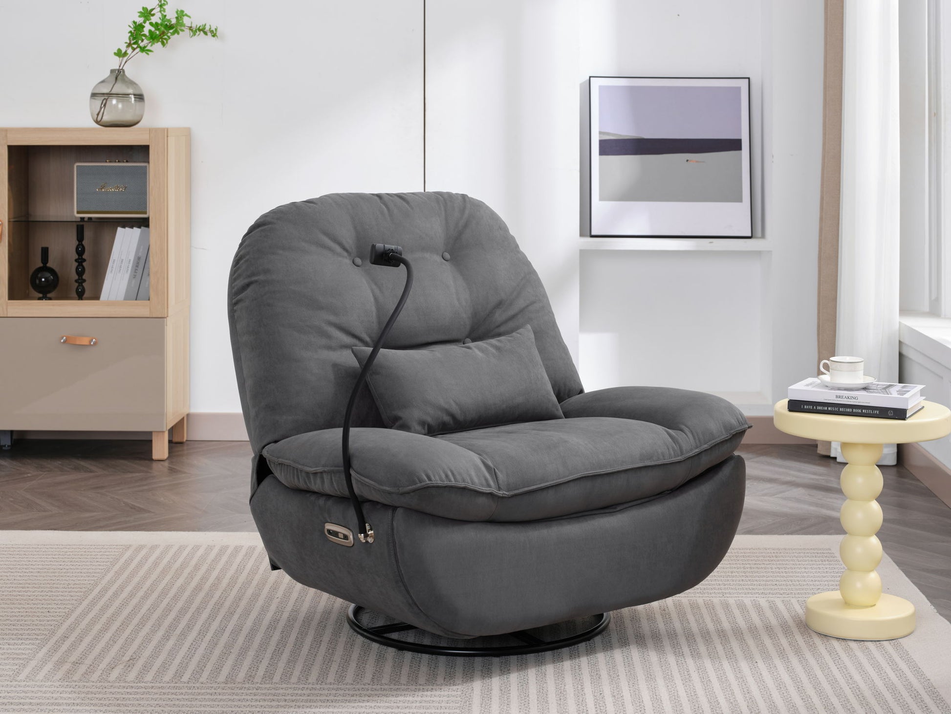 A Power Recliner Swivel Glider with USB Charger and Bluetooth Music Player sits in a modern living room next to a round light-yellow side table, bookshelf, and framed abstract artwork.